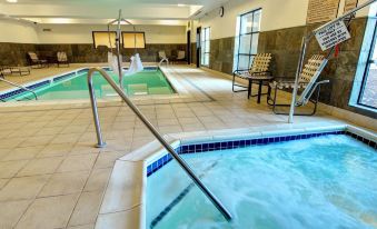 a modern indoor swimming pool with multiple hot tubs , lounge chairs , and umbrellas , providing a relaxing atmosphere at Grand Hotel at Bridgeport