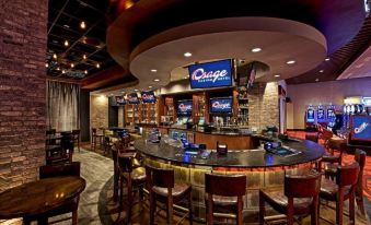 a bar area with multiple tables and chairs , as well as a tv mounted on the wall at Osage Casino Hotel