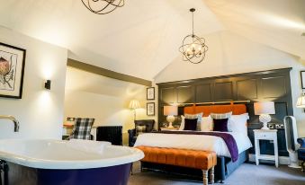 a luxurious bedroom with a large bed , a bathtub in the corner , and a chandelier hanging from the ceiling at Arrow Mill- Brunning and Price