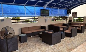 a covered patio area with multiple couches and chairs arranged under a blue canopy , creating an outdoor living space at De Santos Hotel