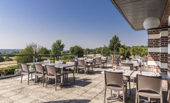 an outdoor dining area with numerous tables and chairs arranged on a patio , providing a pleasant atmosphere for guests at Hôtel du Golf