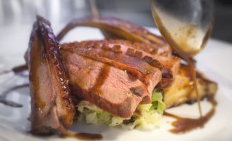 a white plate with a piece of meat on it , accompanied by a fork and knife at The New Inn