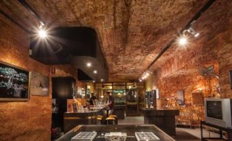 a room with exposed brick walls and a wooden ceiling , featuring a table with framed photographs at Desert Cave Hotel