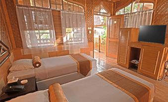 a bedroom with two beds , a television , and a window covered by bamboo blinds , all arranged in a wooden - themed room at Danau Dariza Resort  - Hotel