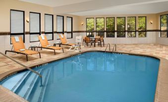 a large swimming pool with blue water is surrounded by lounge chairs and a table at Courtyard Lufkin