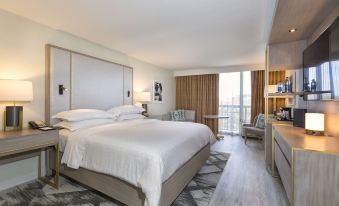 a modern hotel room with a large bed , white bedding , and a view of the city at Sheraton Orlando North Hotel