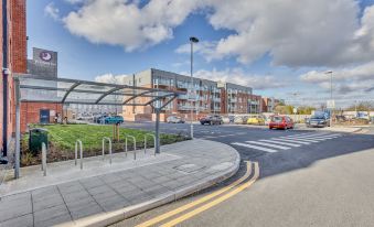 a parking lot with cars parked and a building in the background , under a cloudy sky at Premier Inn Hereford City Centre (Old Market)