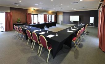 a conference room with a large table surrounded by chairs and a projector screen at the front at Groote Eylandt Lodge