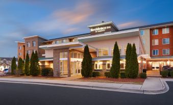 a modern hotel with a large sign on the front , surrounded by trees and a road at Residence Inn Greenville