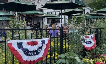 a group of people gathered in a garden , with several flags hanging from a fence at Woodstock Inn, Station and Brewery