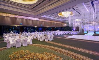 a large banquet hall with white tables and chairs , draped in white tablecloths , is illuminated by chandeliers and chandeliers at Grand Nile Tower