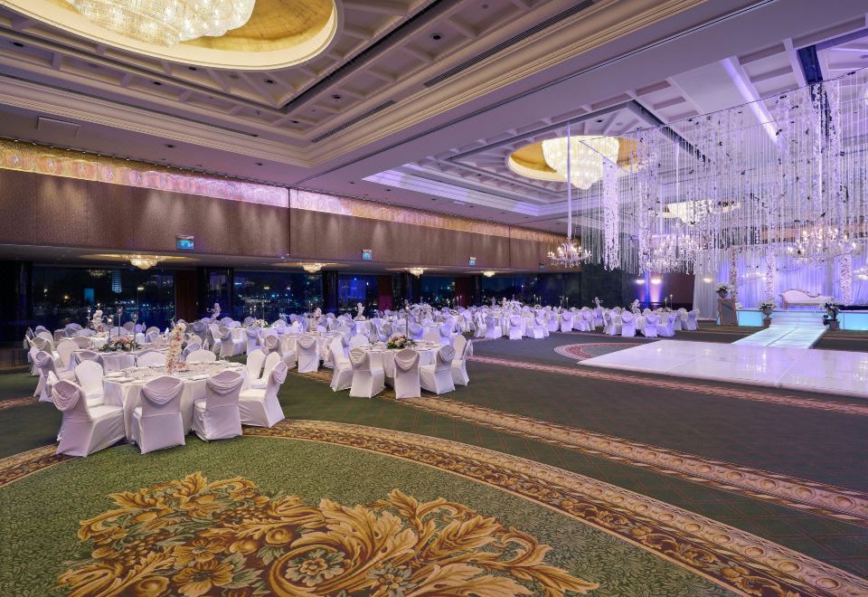 a large banquet hall with white tables and chairs , draped in white tablecloths , is illuminated by chandeliers and chandeliers at Hilton Cairo Grand Nile