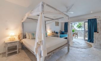 a white four - poster bed with a canopy is in a room with a balcony overlooking the ocean at Chale Island Resort