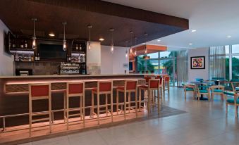 a modern bar area with a long wooden bar and several stools for patrons to sit on at Fairfield by Marriott San Salvador