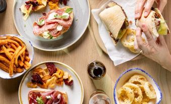 a table filled with various plates of food and a hand reaching for one of the sandwiches at Leonardo Hotel Middlesbrough