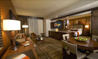 a modern living room with a large flat - screen tv mounted on the wall , a couch , and a dining table at Osage Casino Hotel