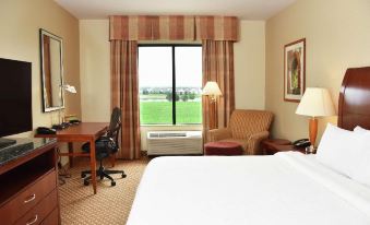 a hotel room with a bed , desk , and chair , as well as a window overlooking the golf course at Hilton Garden Inn Oconomowoc