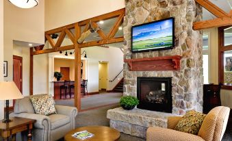 a cozy living room with a stone fireplace and a flat - screen tv mounted on the wall at Atkinson Resort & Country Club