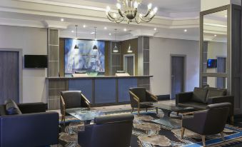 a modern office lobby with a blue carpet , black leather chairs , and a large screen displaying an abstract design at Leonardo Hotel Middlesbrough - Formerly Jurys Inn