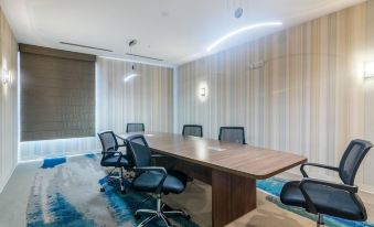 a conference room with a wooden table and black chairs , surrounded by white walls and striped curtains at SpringHill Suites Oklahoma City Downtown/Bricktown