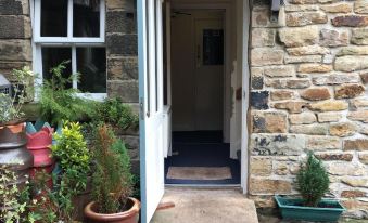 a stone building with a white door and several potted plants on the front porch at The Lawrence