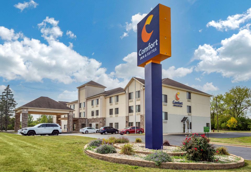 a comfort suites hotel with a large sign in front of it and cars parked nearby at Comfort Inn & Suites North Aurora - Naperville