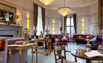 a luxurious hotel lobby with high ceilings , large windows , and multiple seating areas , including couches , chairs , and tables at Kilkea Castle