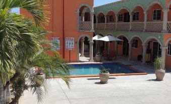 a courtyard with a swimming pool surrounded by multiple buildings , some of which have balconies at Cactus Inn Los Cabos
