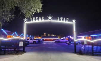 "a large lighted sign with the words "" texas star "" above a parking lot , illuminating the night sky" at Texas Star Lodges