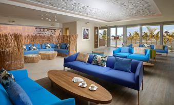 a large , well - lit room with multiple couches and chairs arranged in various positions , creating a comfortable and inviting atmosphere at The Brando
