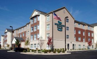 "a hotel with a sign that says "" forest grove inn & suites "" and an american flag in front" at Homewood Suites by Hilton Bloomington