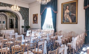 a large , empty room with rows of wooden chairs and chandeliers , possibly for a formal event at The Bear, Cowbridge