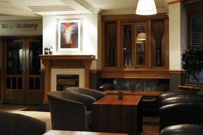 a cozy living room with wooden furniture , including a fireplace , chairs , and a coffee table at Village Hotel Liverpool