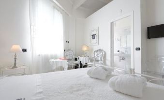 a large white bed with a headboard is in a room with a chair and desk at Hotel San Giovanni