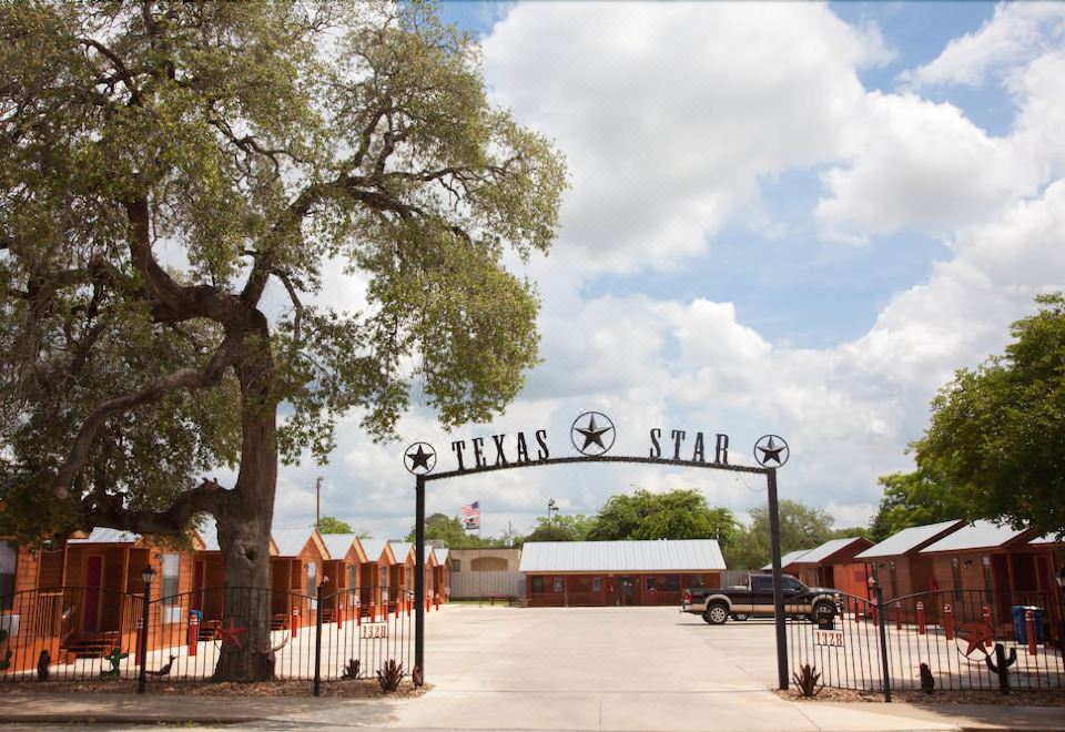 "a gate with the words "" texas star "" written on it , leading to a parking lot and a building" at Texas Star Lodges