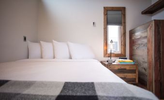 a large bed with white sheets and pillows is in a room next to a window at Bay Point Landing