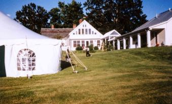 a large white tent is set up on a grassy field with a grassy area in front of it at Whitford House