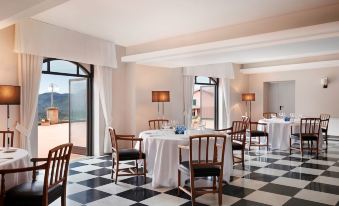 a large , elegant dining room with a black and white checkered floor , multiple round tables , and elegant chairs at Renaissance Tuscany Il Ciocco Resort & Spa