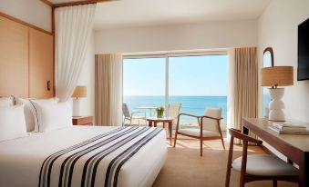 a hotel room with a large window overlooking the ocean , featuring a bed , a chair , and a dining table at Tivoli Marina Vilamoura