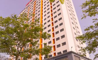 a tall building with a red and yellow striped facade is surrounded by trees and bushes at Tien Loc Palace Hotel