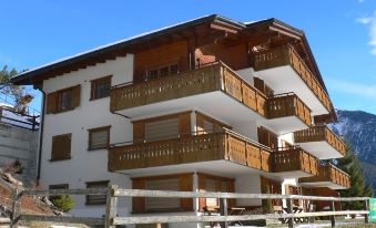 a large , multi - story building with wooden balconies and a snow - covered roof , under a clear blue sky at Eva