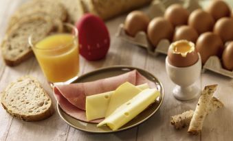 a breakfast table with a variety of food items , including eggs , bread , ham , and cheese at Ibis Lyon Villefranche Sur Saone