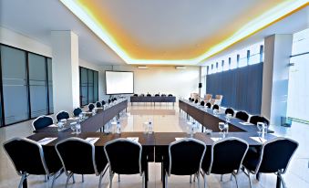 a large conference room with rows of chairs arranged in a semicircle around a long table at Hotel Neo Eltari - Kupang by Aston