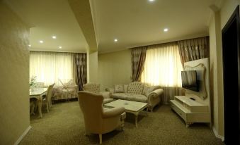 a spacious living room with various furniture , including a couch , chairs , and a dining table at Prestige Hotel
