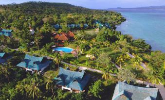 aerial view of a tropical resort with multiple buildings and a pool , surrounded by lush greenery and a lake at Badian Island Wellness Resort