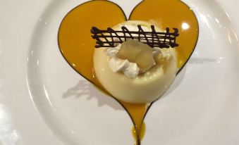 a heart - shaped dessert with a white plate , yellow sauce , and topped with whipped cream is presented on a white plate at Uplawmoor