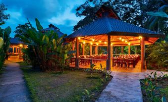 a large outdoor dining area with multiple tables and chairs , surrounded by lush greenery and trees at Laguna Lodge