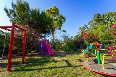 a colorful playground with various play equipment , such as swings , slides , and a jungle gym , surrounded by trees and grass at Hotel Summery