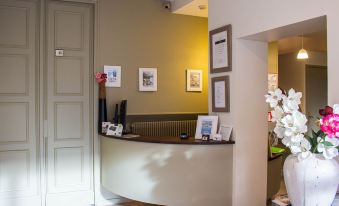 a modern hotel reception area with a curved desk , framed pictures on the wall , and a vase of flowers at Bellevue Beaurivage