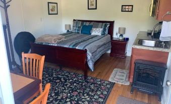 a cozy bedroom with a wooden bed , a rug on the floor , and a dining table in the corner at Micosta Leisure Inn